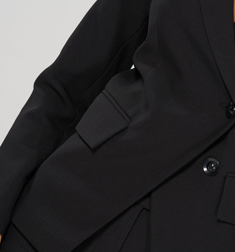 Taillierter Blazer mit raffinierter asymmetrischer Schnittführung, 2 angedeuteten Taschen und großen schwarzen Knöpfen.